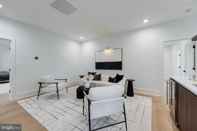 living room with recessed lighting, visible vents, light wood-style flooring, and baseboards