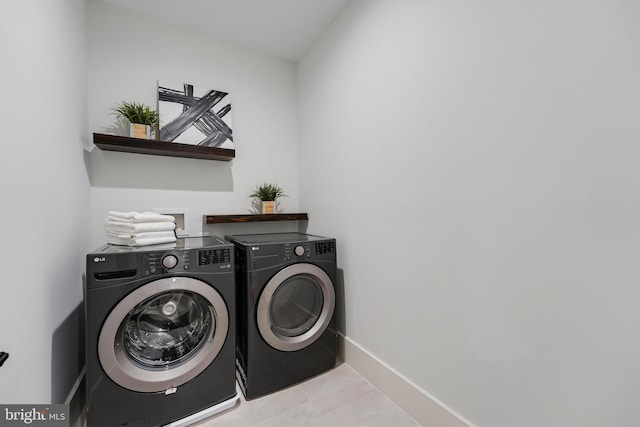 washroom featuring laundry area, tile patterned flooring, washing machine and dryer, and baseboards