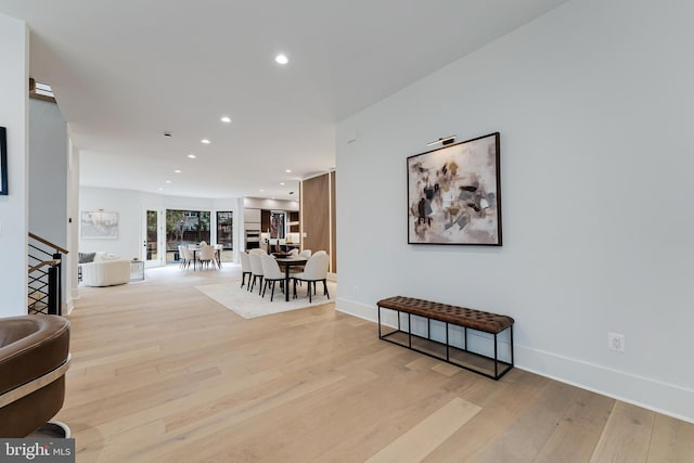 hallway with light wood-style floors, baseboards, stairway, and recessed lighting