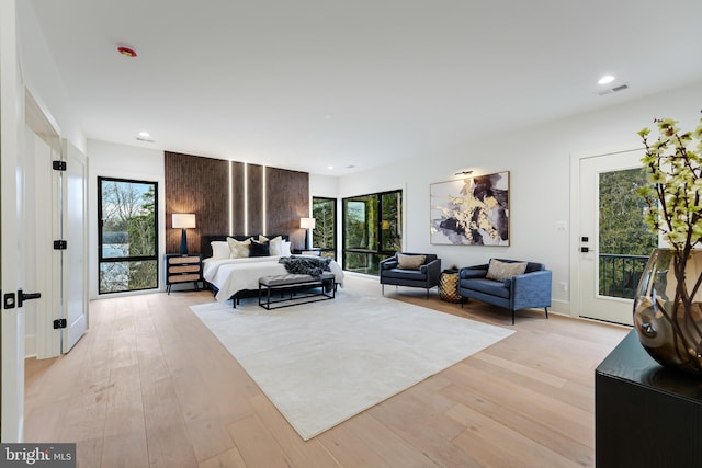 bedroom featuring access to outside, visible vents, light wood finished floors, and multiple windows