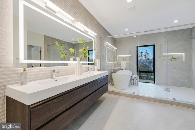 full bath with tile walls, double vanity, a sink, a shower stall, and a freestanding tub