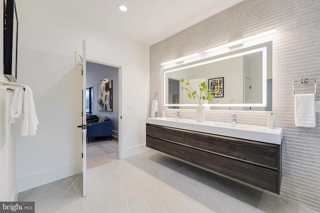 bathroom featuring tile patterned flooring, connected bathroom, a sink, baseboards, and double vanity