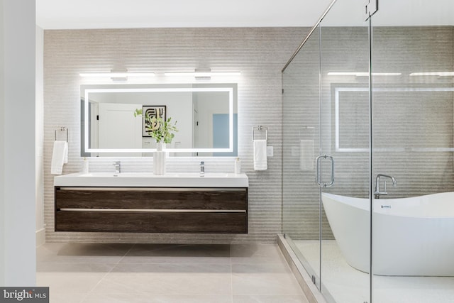 bathroom with double vanity, a soaking tub, a shower stall, and tile patterned floors