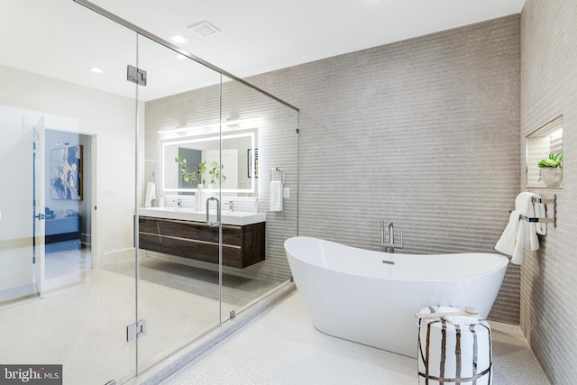 full bath featuring a freestanding bath, vanity, a shower stall, tile walls, and recessed lighting