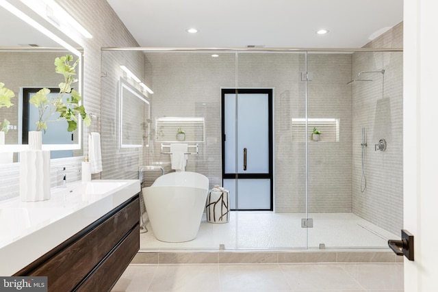 bathroom featuring a stall shower, tile patterned floors, a freestanding bath, vanity, and tile walls