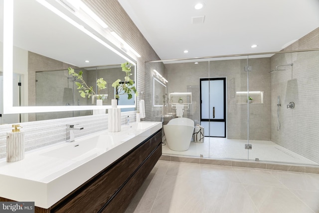 full bathroom with tile walls, double vanity, a freestanding bath, a sink, and a shower stall