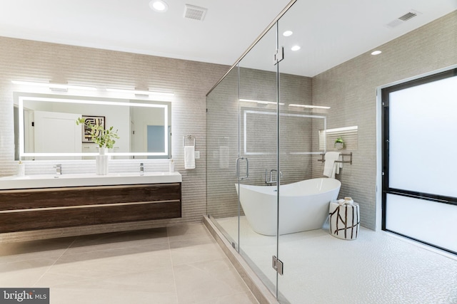 full bathroom featuring double vanity, a soaking tub, visible vents, and tile walls