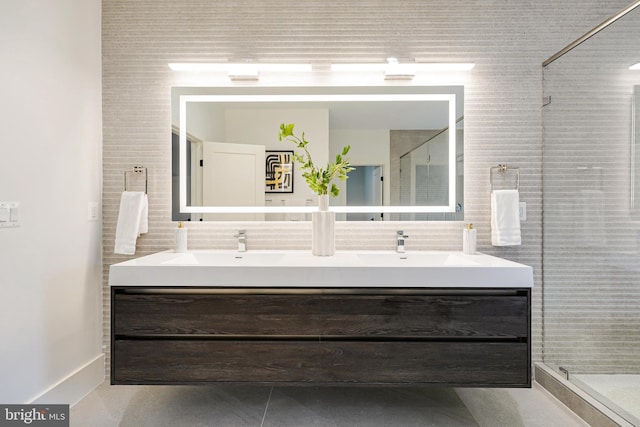 bathroom with decorative backsplash, a tile shower, a sink, and double vanity