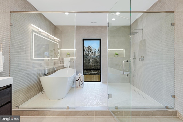 full bath with a stall shower, a freestanding tub, and vanity