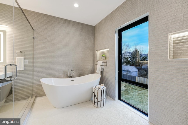 bathroom featuring a stall shower, a freestanding tub, and tile walls