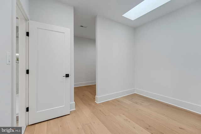 interior space with light wood-style flooring, a skylight, visible vents, and baseboards