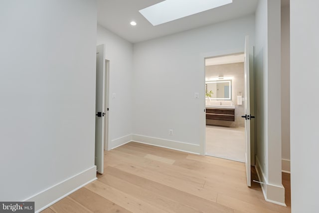 interior space featuring light wood-type flooring, recessed lighting, a skylight, and baseboards