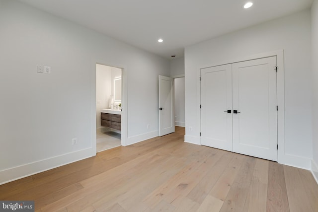 unfurnished bedroom with recessed lighting, a closet, light wood-style flooring, ensuite bath, and baseboards