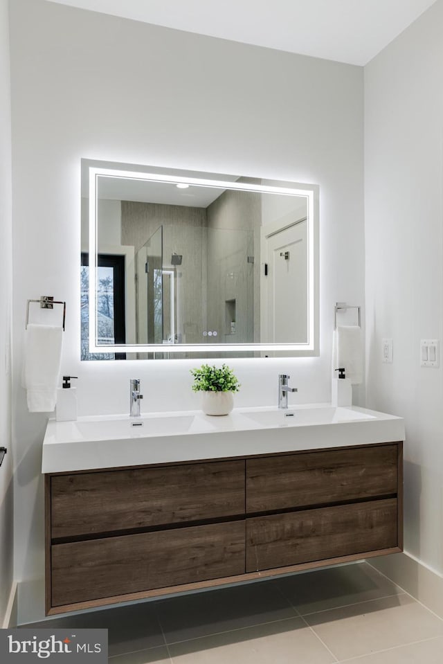 full bath with double vanity, a shower stall, a sink, and tile patterned floors