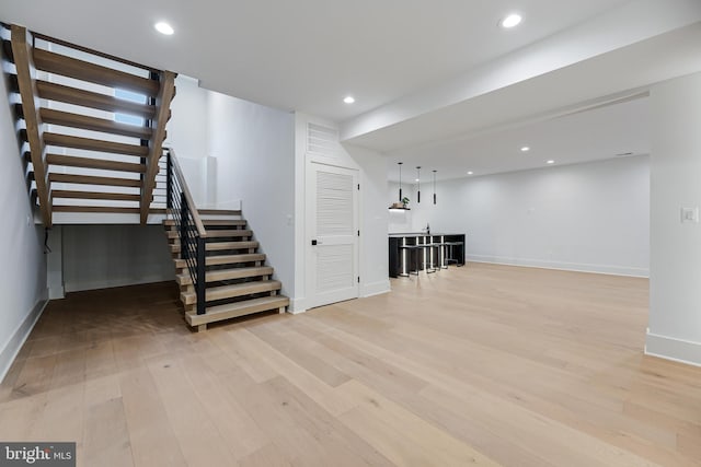 finished basement with baseboards, stairway, recessed lighting, and light wood-style floors