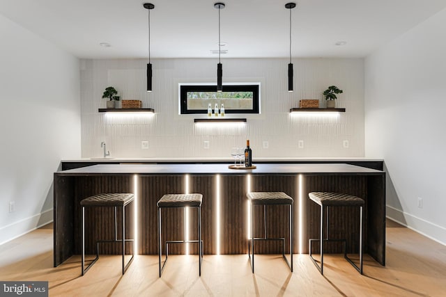 bar with tasteful backsplash, wet bar, pendant lighting, and baseboards