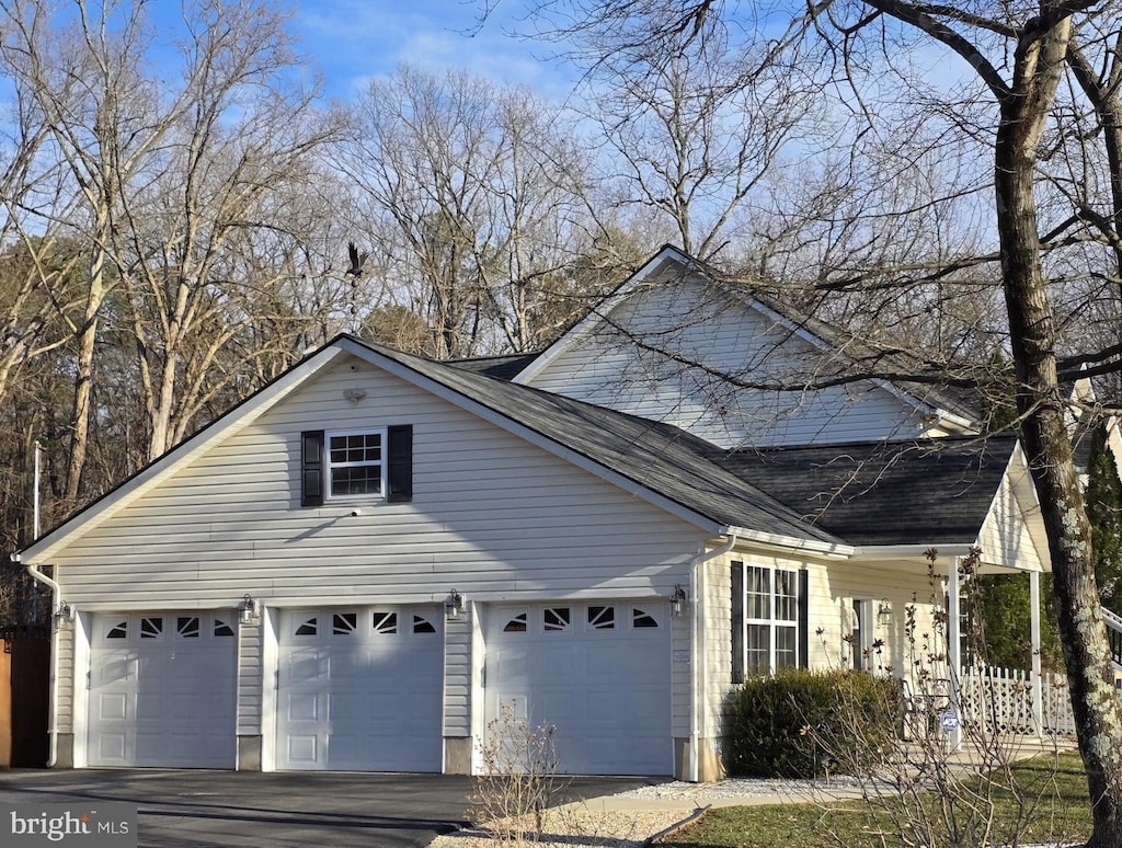 view of property exterior featuring roof with shingles and driveway