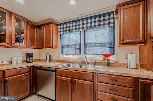 kitchen featuring a sink, glass insert cabinets, light countertops, and stainless steel dishwasher