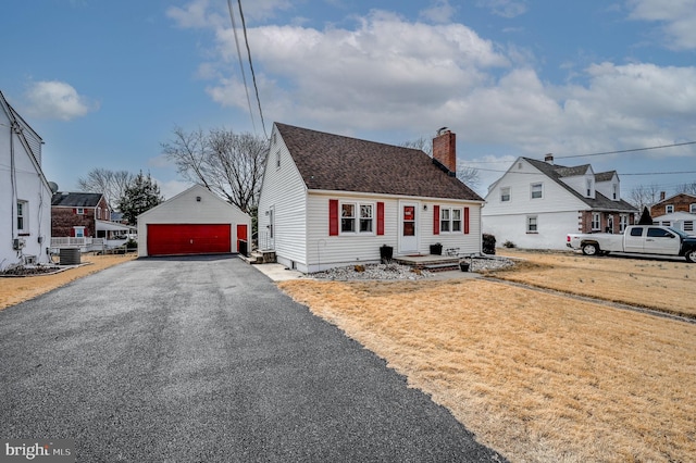 view of front of home with an outbuilding, cooling unit, a detached garage, a chimney, and a front yard