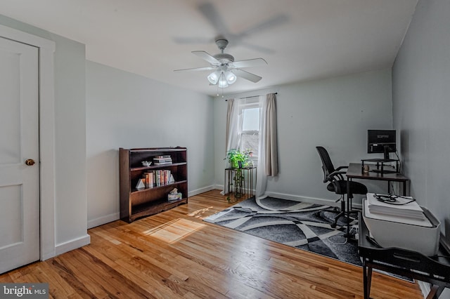 exercise area featuring ceiling fan, baseboards, and wood finished floors