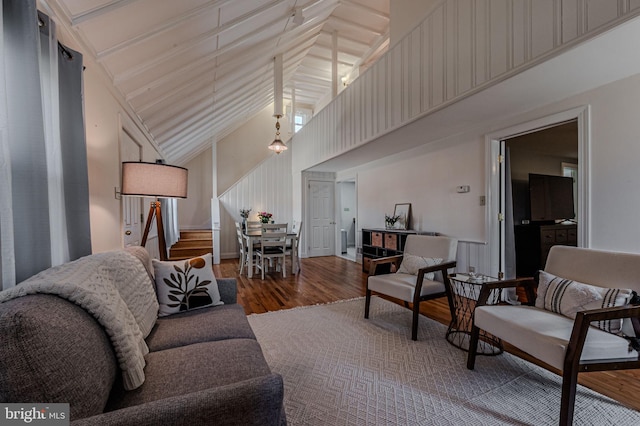 living room featuring high vaulted ceiling, stairway, and wood finished floors