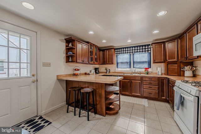 kitchen featuring a peninsula, white appliances, plenty of natural light, and open shelves