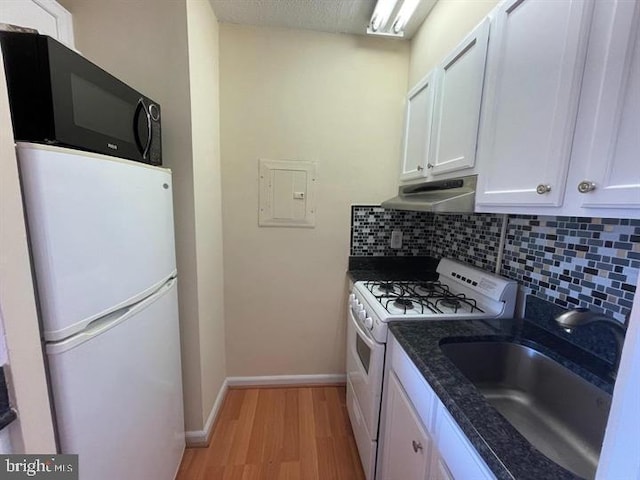 kitchen with under cabinet range hood, white appliances, a sink, white cabinets, and decorative backsplash