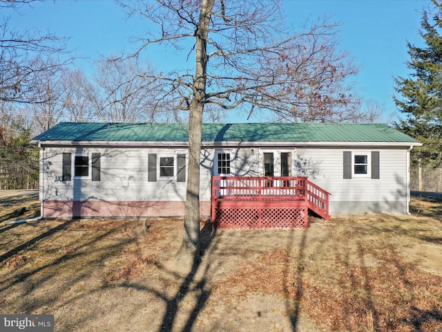 rear view of property featuring a yard, metal roof, and a wooden deck