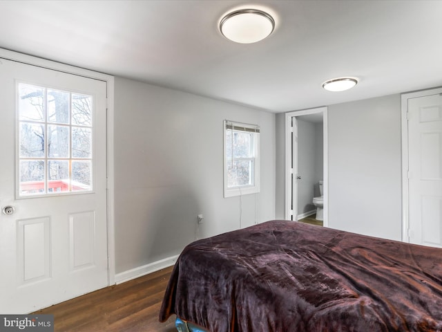 bedroom with baseboards, dark wood-style flooring, and ensuite bathroom