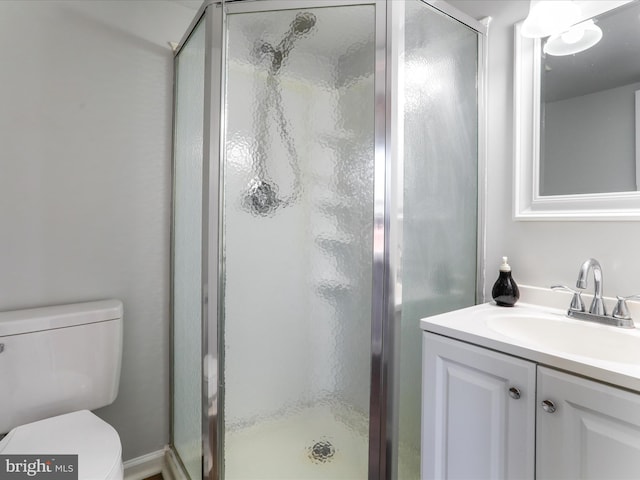 bathroom with toilet, a stall shower, and vanity