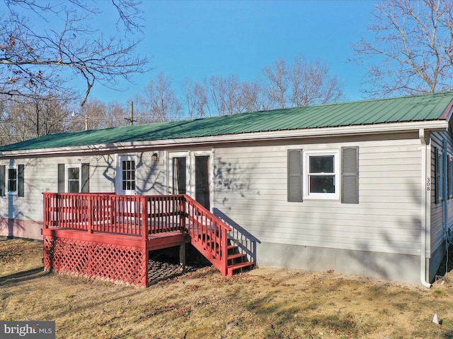 back of house with a deck, metal roof, and a yard