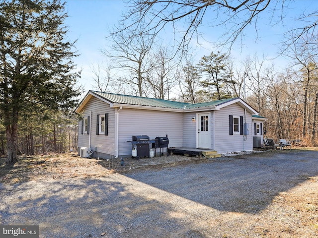 view of side of home with central air condition unit, driveway, and metal roof