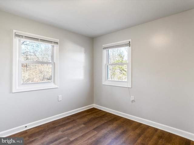 unfurnished room featuring baseboards and dark wood finished floors