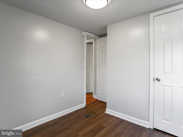 unfurnished bedroom with dark wood-style floors, visible vents, and baseboards