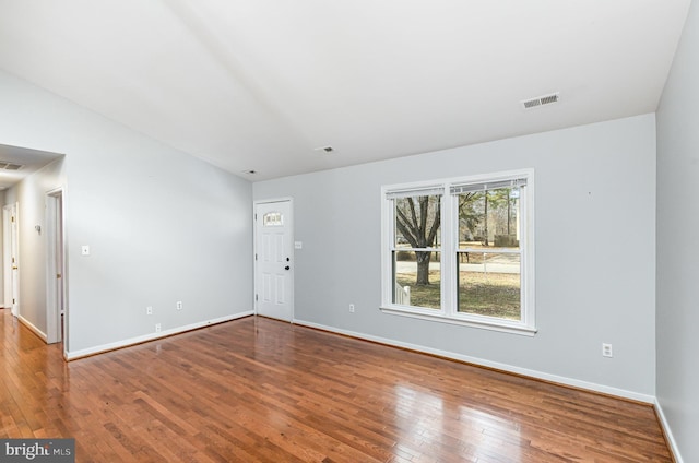 unfurnished room featuring hardwood / wood-style flooring, visible vents, and baseboards