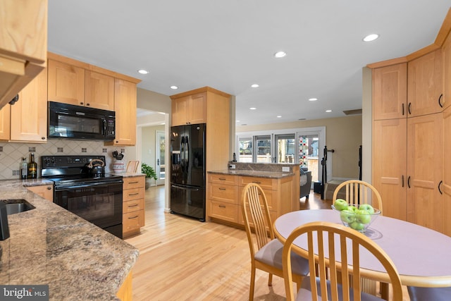 kitchen featuring black appliances, light brown cabinets, tasteful backsplash, light wood finished floors, and light stone countertops