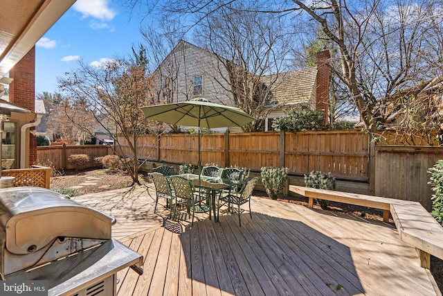 wooden deck featuring outdoor dining area, a fenced backyard, and a grill