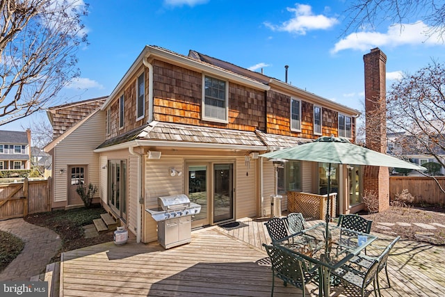 rear view of property with a chimney, fence private yard, a wooden deck, and outdoor dining area