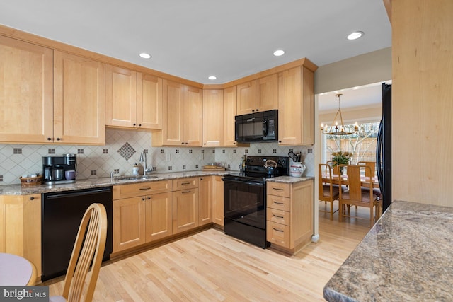 kitchen with light brown cabinetry, light wood-style flooring, an inviting chandelier, black appliances, and a sink