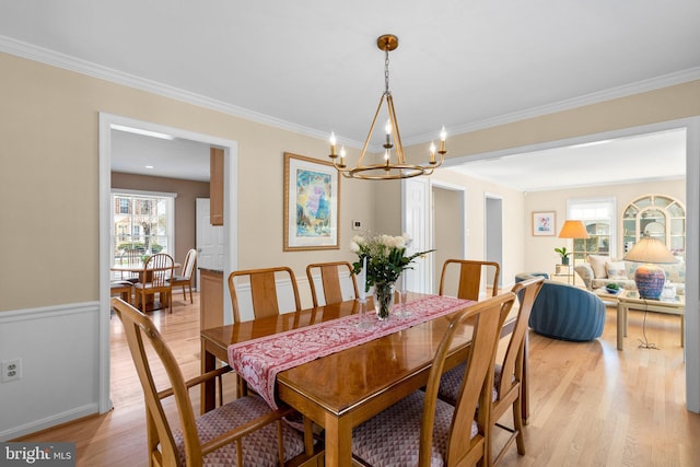 dining room featuring light wood-style flooring, a notable chandelier, and ornamental molding