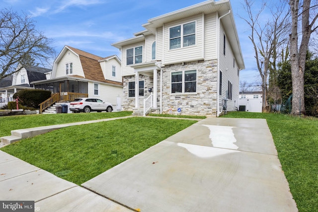 view of front of property featuring stone siding, a front yard, and a sunroom