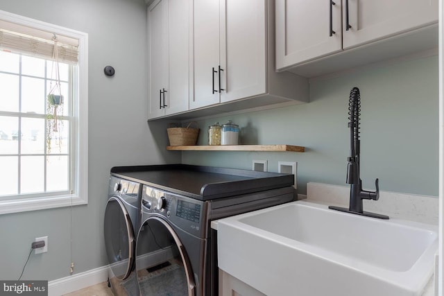 laundry room with washer and dryer, cabinet space, a sink, and baseboards