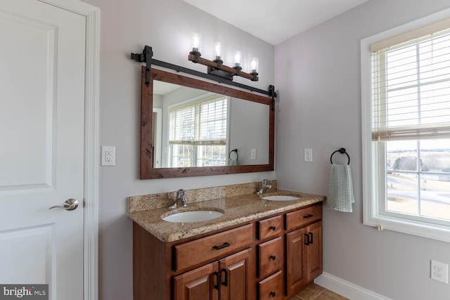 bathroom featuring double vanity, a sink, and baseboards