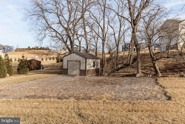 view of yard featuring driveway, a shed, an outdoor structure, and a detached garage