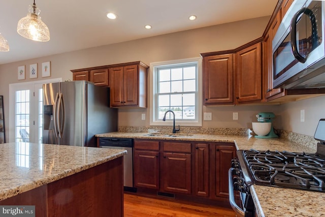 kitchen featuring light stone countertops, stainless steel appliances, pendant lighting, a sink, and recessed lighting