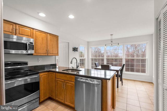 kitchen with light tile patterned floors, stainless steel appliances, a peninsula, a sink, and brown cabinets