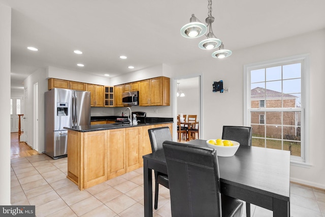 kitchen with appliances with stainless steel finishes, glass insert cabinets, a peninsula, hanging light fixtures, and recessed lighting