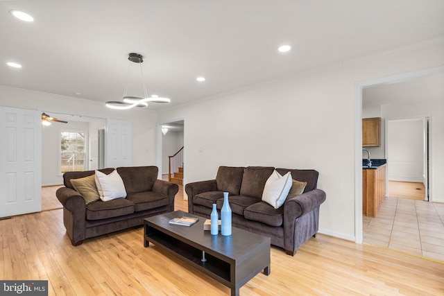 living room with baseboards, stairway, crown molding, light wood-type flooring, and recessed lighting