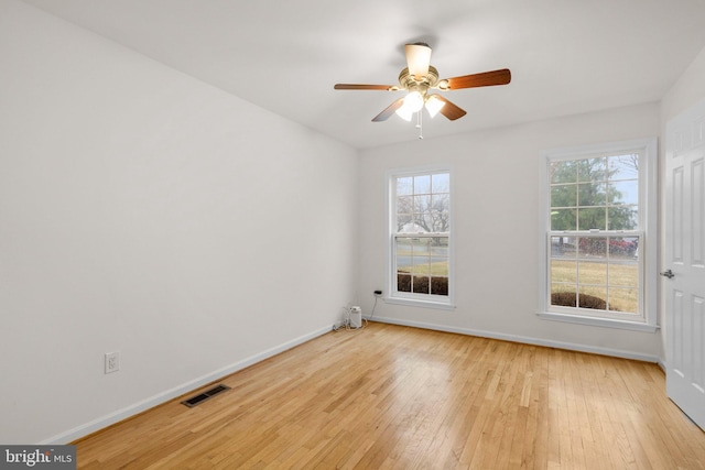 empty room with a ceiling fan, baseboards, visible vents, and hardwood / wood-style floors