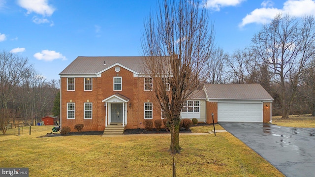 colonial home featuring a garage, brick siding, driveway, and a front lawn